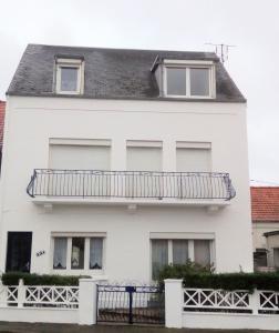 a white house with a balcony on it at Roseau in Berck-sur-Mer