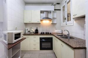 a white kitchen with a microwave and a sink at Maison Lamic 2 in Lloret de Mar