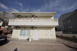 a white house with a balcony on top of it at Apartmani Znaor in Baška Voda