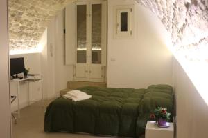a bedroom with a green bed and a desk at Specula Domus - Ibla in Ragusa