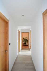 a hallway leading into a home with white walls and wooden doors at Apartamento Vila O Valadouro in Ferreira