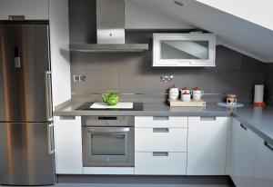 a kitchen with white cabinets and a stainless steel refrigerator at Apartamento Vila O Valadouro in Ferreira