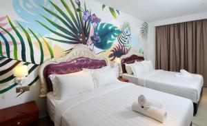 two beds in a hotel room with a mural at Hotel de Art USJ 21 in Subang Jaya