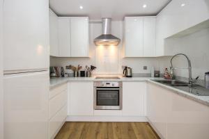 a white kitchen with white cabinets and a sink at On the Quay in Harwich