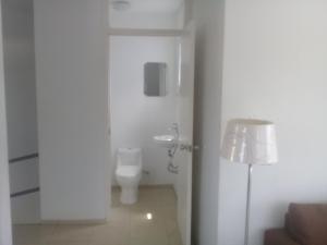 a bathroom with a toilet and a sink and a lamp at Yolo Apartment in Willemstad