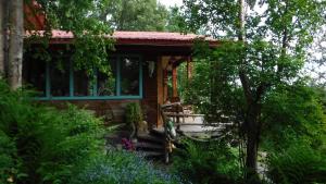 eine kleine Hütte mit einer Veranda sowie Bäumen und Blumen in der Unterkunft Brigitte's Bavarian Bed und Breakfast in Homer