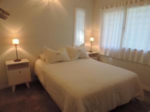 a bedroom with a white bed with two night stands at Puerto de Lilas in Las Gaviotas
