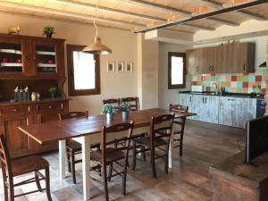 a kitchen and dining room with a wooden table and chairs at Cal Nenot in Puigcercos