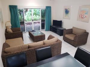 een woonkamer met een bank en stoelen en een tv bij Mango Tree Holiday Apartments in Port Douglas