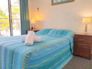 a bedroom with a blue bed with towels on it at Mango Tree Holiday Apartments in Port Douglas