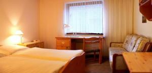 a hotel room with a bed and a desk and a window at Siegerland-Hotel in Freudenberg