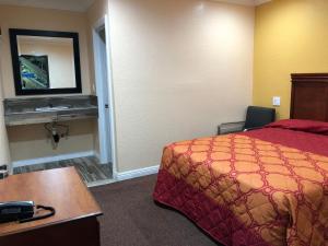 a hotel room with a bed and a desk and a mirror at Rosa Bell Motel - Los Angeles in Los Angeles