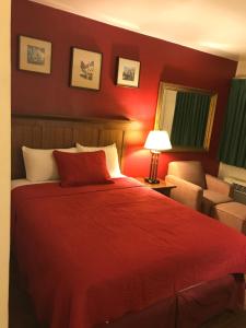 een rode slaapkamer met een bed en een stoel bij Canyonlands Motor Inn in Monticello