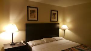 ein Schlafzimmer mit einem Bett mit zwei Lampen und einem Telefon in der Unterkunft America's Best Inn - Macon in Macon