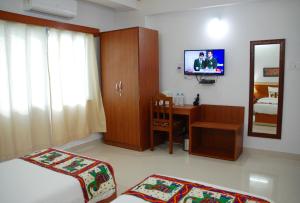 um quarto com uma cama, uma secretária e uma televisão em The Bodhgaya Hotel School em Bodh Gaya