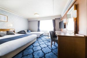 a hotel room with a bed, chair, and nightstand at Senri Hankyu Hotel Osaka in Toyonaka