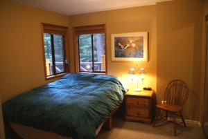 a bedroom with a bed and a chair and a window at Whistler Superior Properties in Whistler