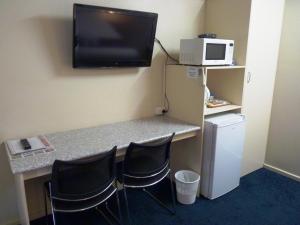 a room with a desk with two chairs and a microwave at International Lodge Motel in Mackay