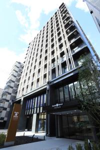 a large white building with a sign in front of it at Smile Hotel Premium Osaka Hommachi in Osaka