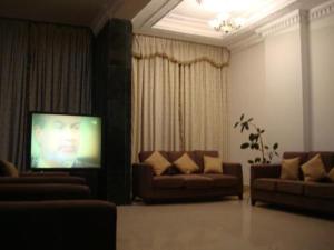 ein Wohnzimmer mit 2 Sofas und einem Flachbild-TV in der Unterkunft Red Tower Furnished Apartments in Kuwait