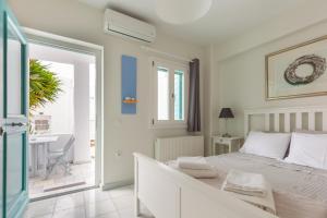 Habitación blanca con cama y balcón. en PEBBLES 1BD house with Sea View in the heart of Naousa en Náousa