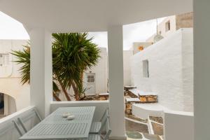 Un balcón blanco con una mesa y una palmera en PEBBLES 1BD house with Sea View in the heart of Naousa en Náousa