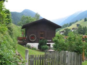 una pequeña casa en una colina con una valla en Ferienhaus Wassermühle, en Maria Luggau