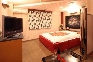 a bedroom with a bed and a flat screen tv at Hotel Kyoto (Adult Only) in Zentsuji