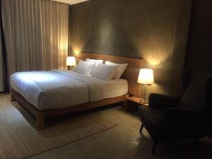 a bedroom with a bed with two lamps and a chair at Inchantreedoopool in Kanchanaburi City