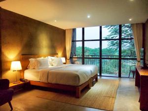 a bedroom with a large bed and a large window at Inchantreedoopool in Kanchanaburi City