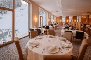 a restaurant with white tables and chairs and windows at Wellness Hotel Montis in Mozirje