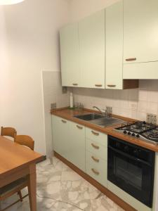 eine Küche mit weißen Schränken, einer Spüle und einem Tisch in der Unterkunft Appartamento via Roma 56 in Monterosso al Mare