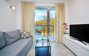 a living room with a couch and a large window at Dwie Sosny Apartament 38 - Perła in Ustronie Morskie