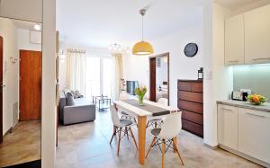 a kitchen and a living room with a table and chairs at Dwie Sosny Apartament 38 - Perła in Ustronie Morskie
