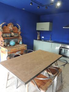 a kitchen with a wooden table and a blue wall at Domaine Houillon in Faucon