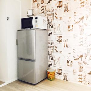 a microwave on top of a refrigerator in a kitchen at Guest House Fukuoka W302 in Kasugabaru