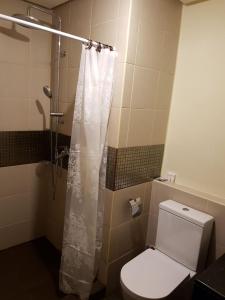 a bathroom with a white shower curtain and a toilet at Azure Urban Resort and Residences by Rosary in Manila