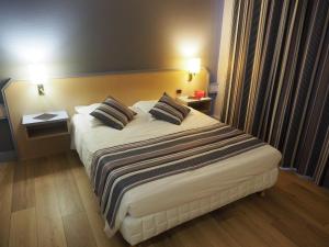 a hotel room with a large bed with two pillows at Logis Hotel Restaurant l'Amandois in Saint-Amand-Montrond +10 photos