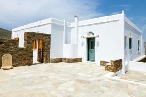 a white church with a green door on a stone patio at Imarkellis Tinos Boutique Villas in Panormos