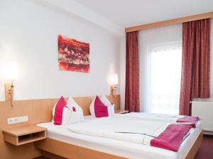 a bedroom with a large bed with red and white pillows at Pension Schrägers in Königstein an der Elbe