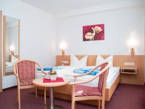 ケーニッヒスシュタイン・アン・デ・エルベにあるPension Schrägersのベッド、テーブル、椅子が備わるホテルルームです。
