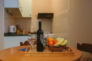 a wooden tray with a bottle of wine and a bowl of fruit at Studio apartman Salopek in Ogulin