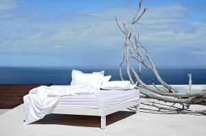 a bed with white sheets and pillows on a balcony at PG - Beach House in Sintra