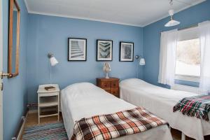 2 camas en una habitación con paredes azules en Ängsö Fishermans Cottage en Västerås