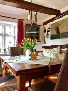 a dining room with a wooden table with flowers on it at Haus am Hafen - romantisch unter Reet, Garten mit Strandkorb und Terrasse in Prerow