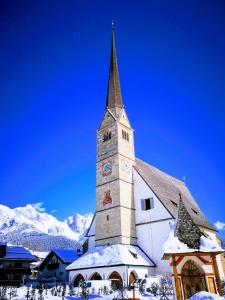 een kerk met een klokkentoren in de sneeuw bij Ferienwohnung Klappacher in Maria Alm am Steinernen Meer