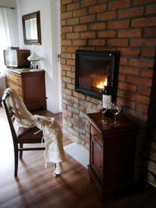 a living room with a fireplace and a chair with wine glasses at Chata na Zielonym Wzgórzu in Garcz