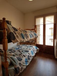 een slaapkamer met een bed met een dekbed bij Cal Sastre in Castellar de NʼHug