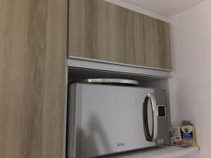 La cocina está equipada con microondas y armarios de madera. en Apartamento Cabo Branco, en João Pessoa