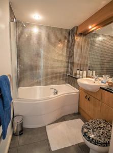 a bathroom with a tub and a sink at Coastal Apartments - Wales in Swansea